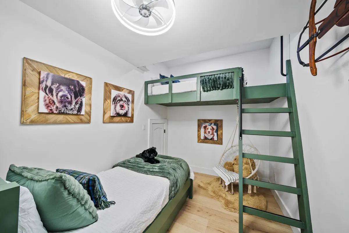 Inside, a whimsical bunk bed setup is adorned with playful dog portraits, a textured blanket, and a woven chair. The inviting nook exudes charm and creativity, hinting at hidden spaces and joyful play for kids, while also providing cozy accommodations for resting or reading.